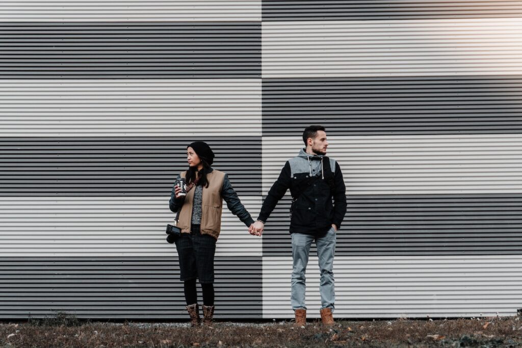 Couple holding hands but facing apart