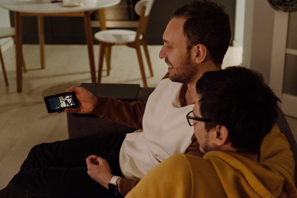 Couple cuddling on the sofa watching a video on their phone