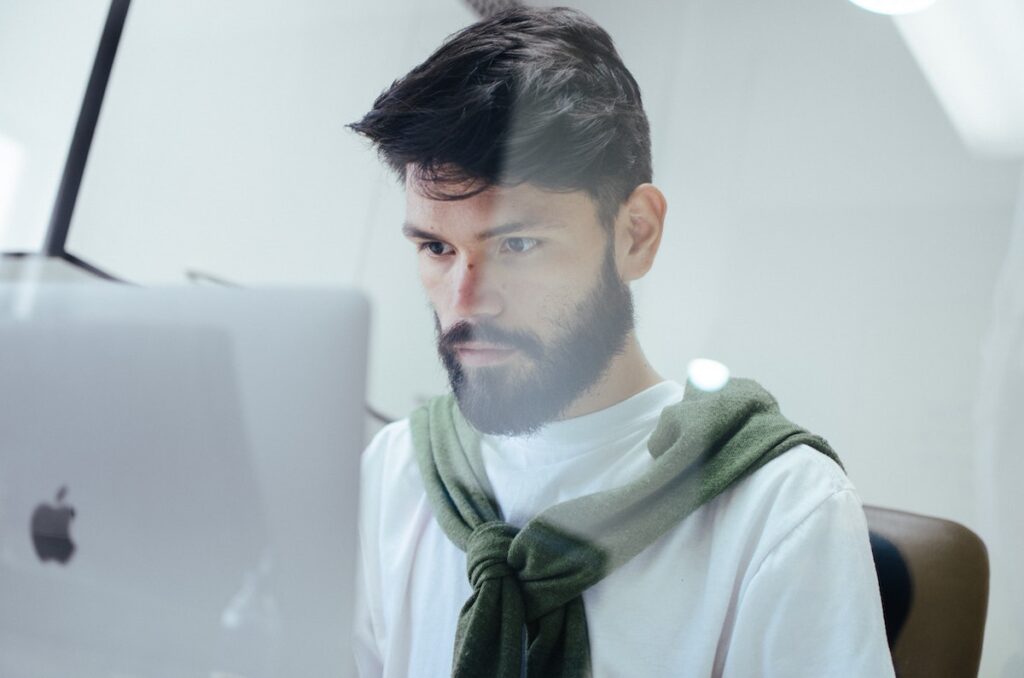 Image of a man with dark hair sitting at a laptop