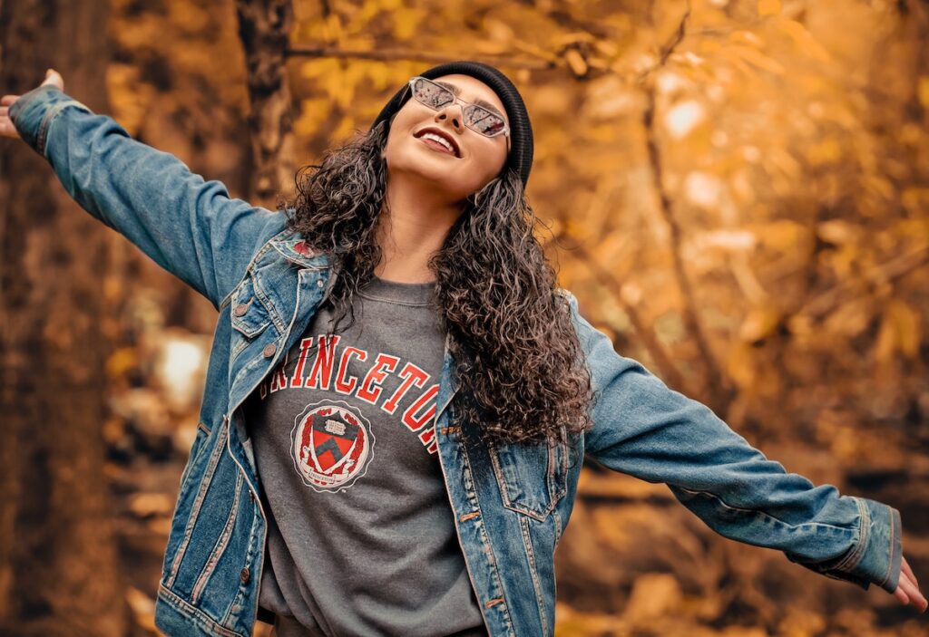 Image of a young woman smiling amongst autumn tress