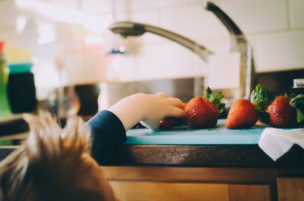 Young child reaching for a strawberry