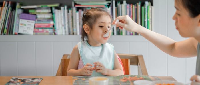 A toddler is fed baby food