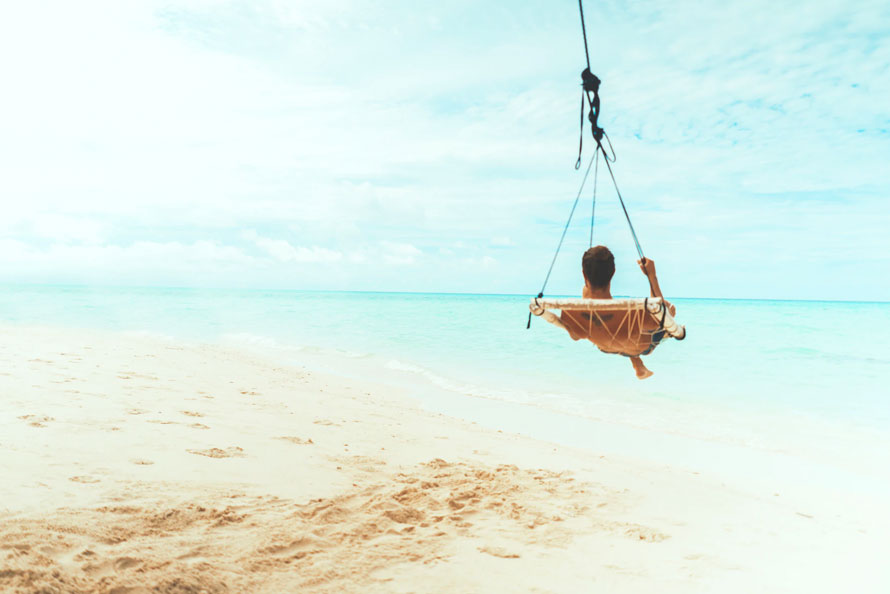 Man in a hammock on a beach over looking the sea