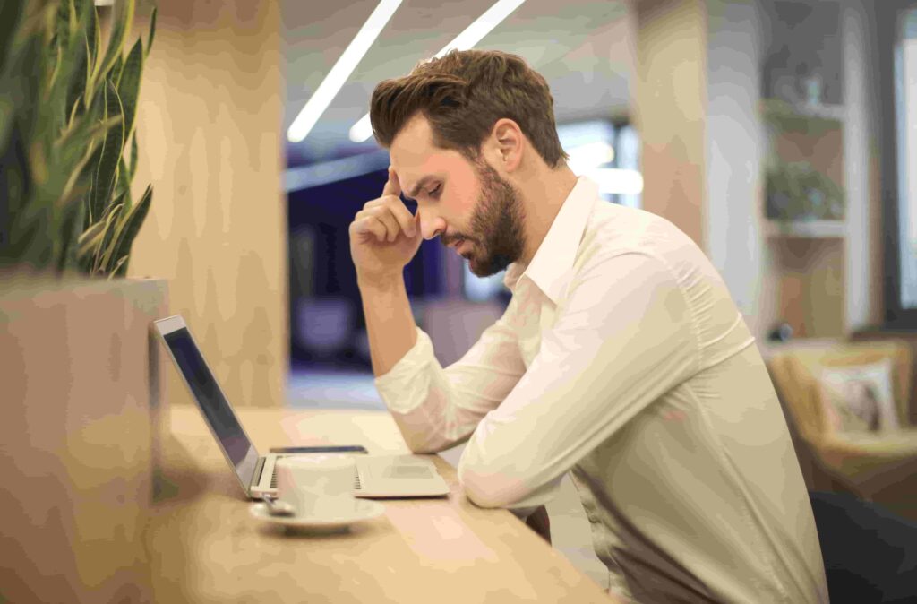 A man sits with his hand on his head as he works