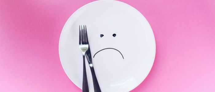 An empty plate with a sad smilie face drawn on it