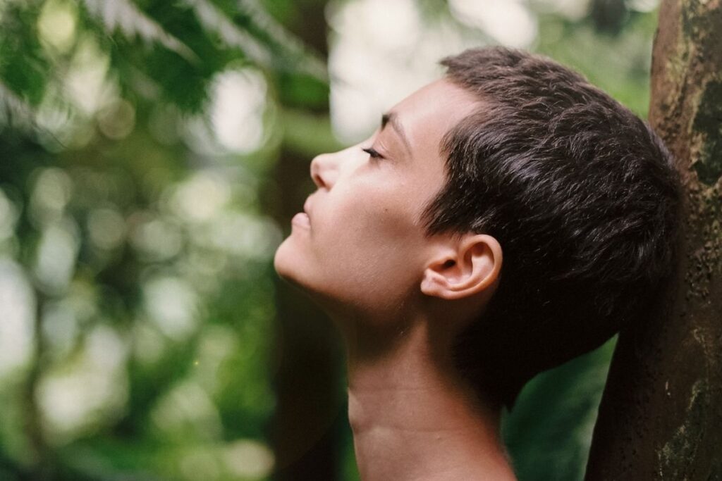 Woman leaning on tree in sunlight