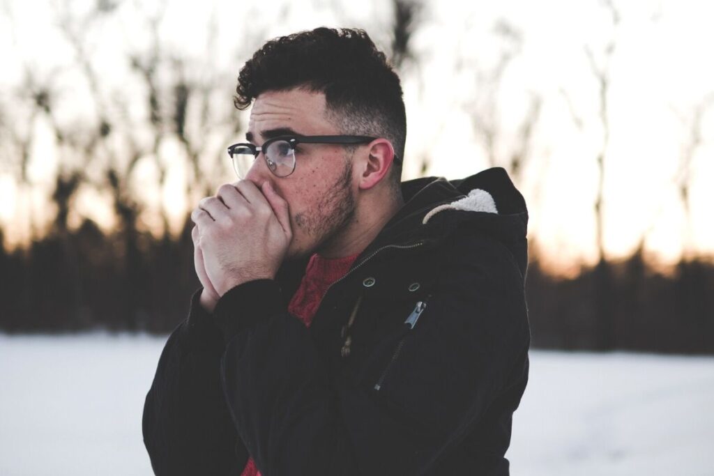 Man in snow blowing on hands