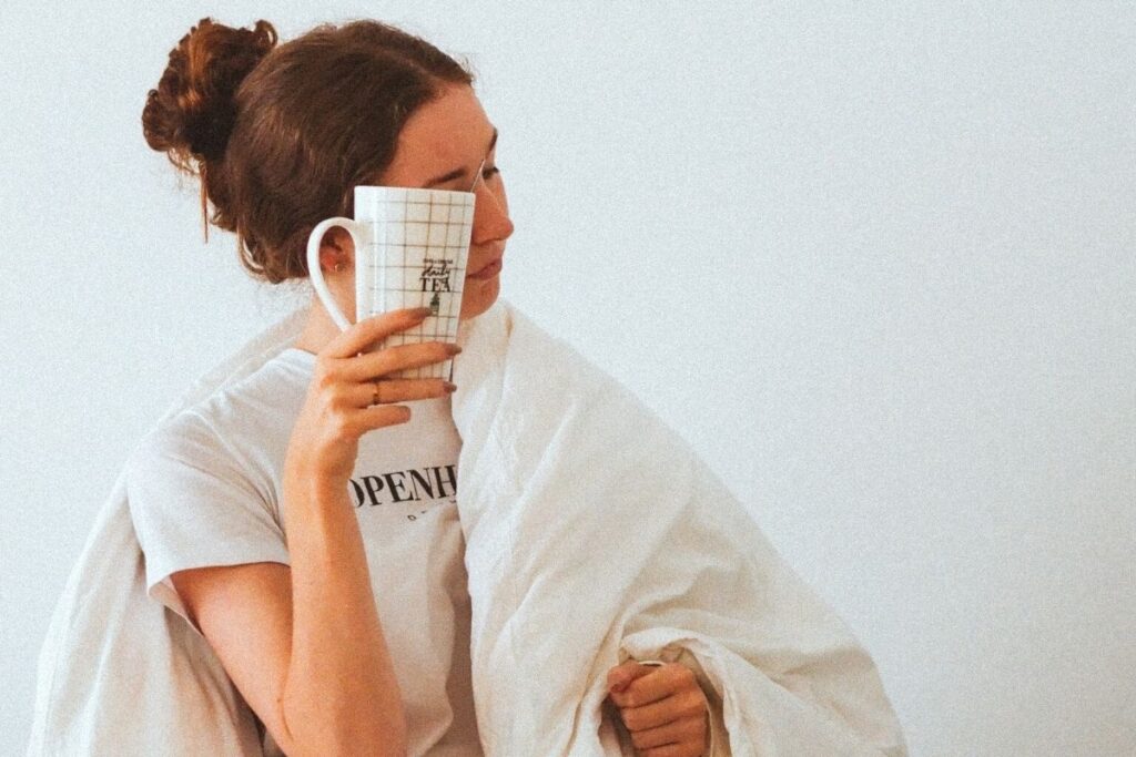 Woman in duvet holding cup