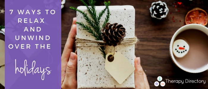 a hand holds a wrapped gift with a minecone decoration, a cup of hot chocolate to one side