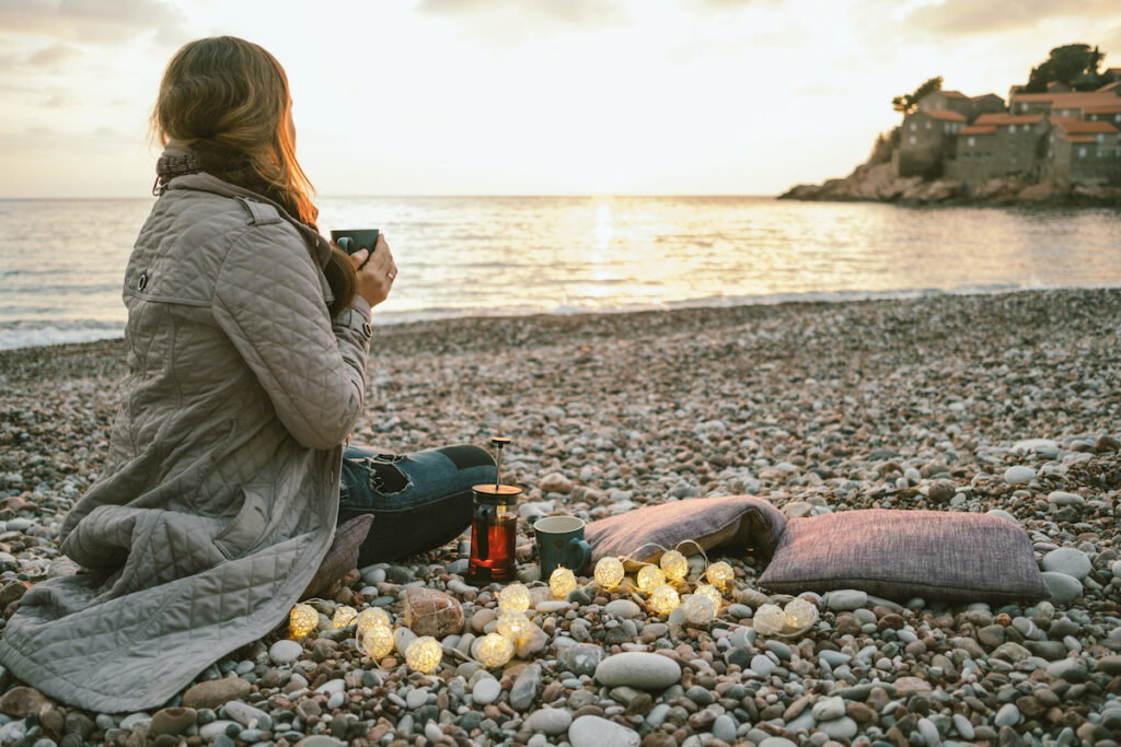 Woman sat on the beach drinking tea