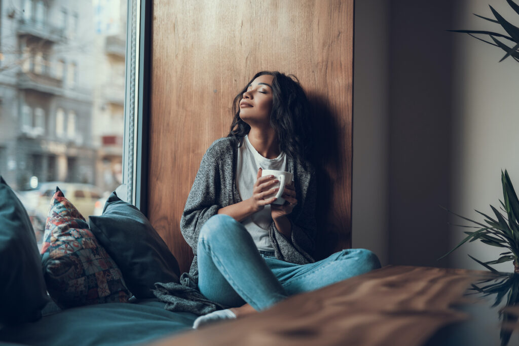 Woman with mug sitting on window