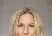 Woman wearing a light grey turtleneck sweater and smiling softly
