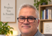 Photo of a middle aged man in a study full of books