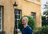 An image of a smiling man standing outside a building.