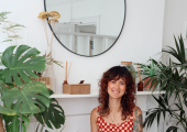 Therapist Yasmin of Kinder Minds Inclusive Therapy sitting down, surrounded by plants