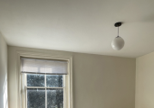 The room is large and airy, set within a Grade II listed building with bay windows overlooking trees