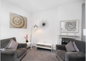 A quiet therapy room with two soft chairs and a painting of the sun on the wall.