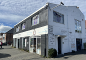 Building with a dark wooden front and a white side.