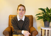 This is am image of a therapist sat in an armchair giving therapy with a plant