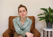 A therapist sits on an armchair with a peace lily beside her on a table