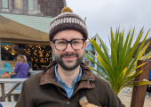 This is an image of Jason sat at a table with Luna, an Irish Terrier.
