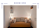 A two-seater sofa, therapists chair, sand tray, and creative therapy supplies.