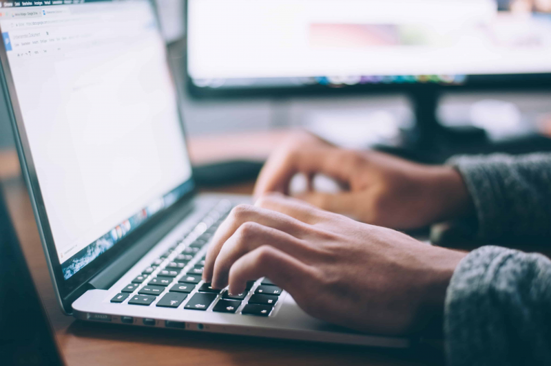 Close-up of someone typing on their laptop.