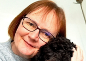 Photo of Julie Osborn, ADHD coach and Business Psychologist, smiling warmly whilst cuddling her dog