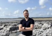 Adam Print standing on beach looking at camera, ready to discuss coaching.