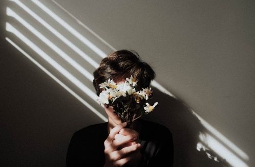 person hiding face with flowers