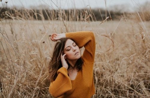 woman with eyes closed in field