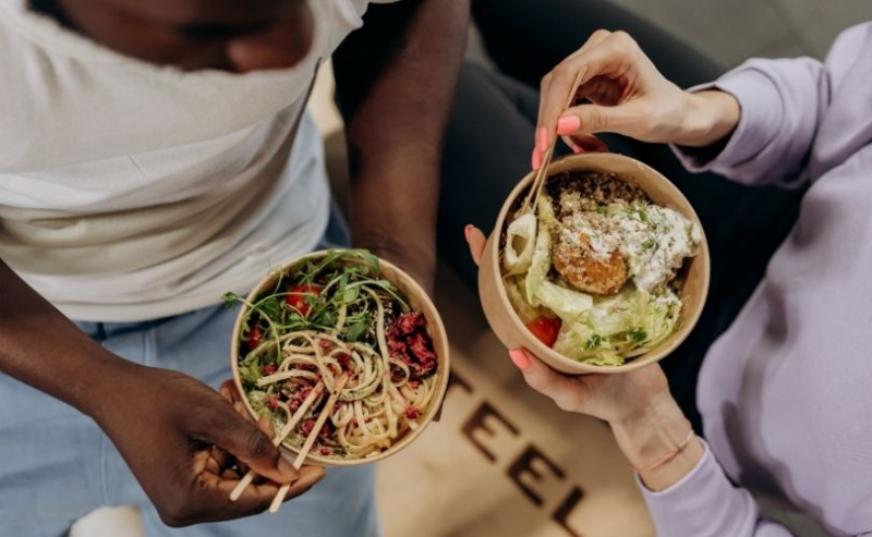 Two friends using chopsticks with bowls of food
