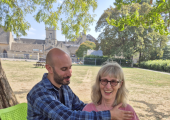 A lady laughing whilst sitting, as Simon works with her