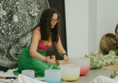 This is an image of a woman playing crystal singing bowls